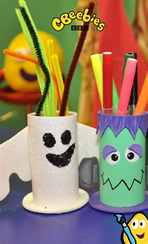 some pencils and markers are sitting in cups with faces painted on them, along with other items