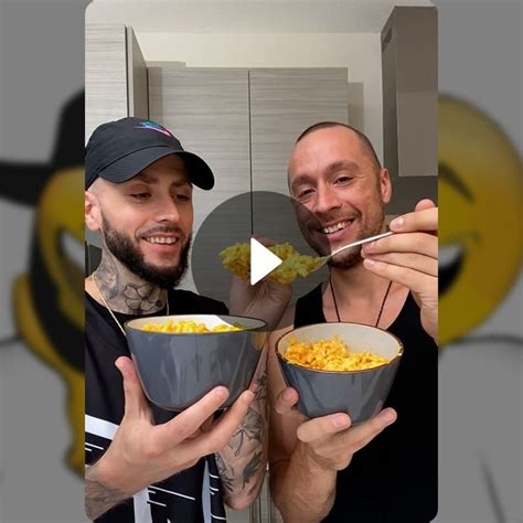 two men holding bowls of food in front of their faces and smiling at the camera