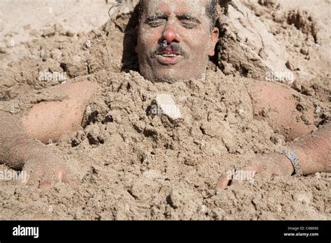 A man buried in the sand on the beach on the coast of Red Sea in Aden, Yemen Stock Photo - Alamy