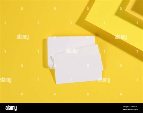 Blank white rectangular business card on creative yellow background from sheets of paper with ...