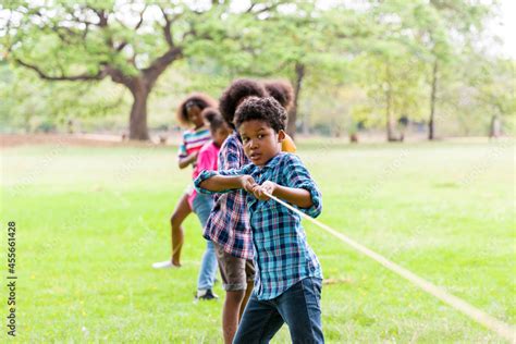 Group of African American boy and girl playing tug of war together in ...