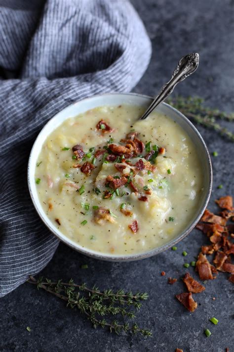 a bowl of potato soup with bacon and parsley in it on a gray surface