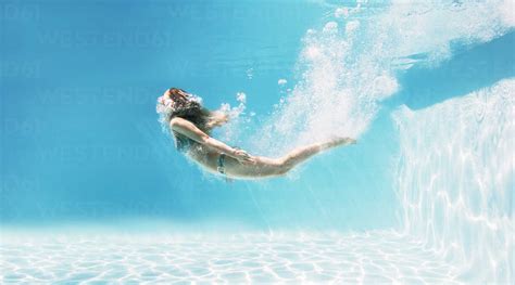 Woman swimming underwater in swimming pool stock photo