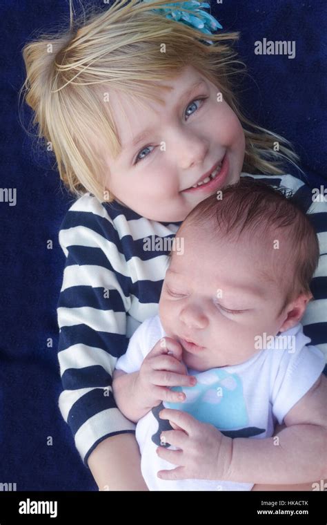 big sister holding newborn baby brother Stock Photo - Alamy