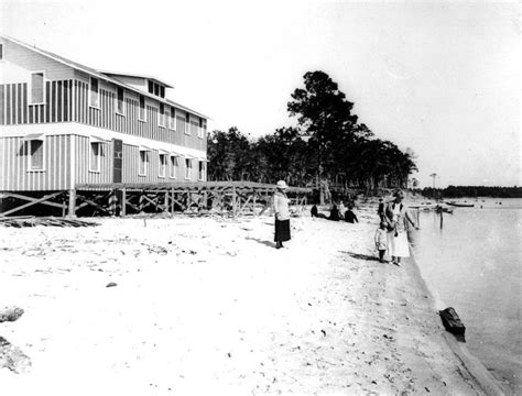 an old black and white photo of people on the beach in front of a building