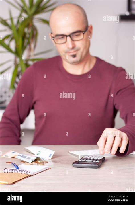 Man doing economic calculations at office table with a calculator Stock Photo - Alamy