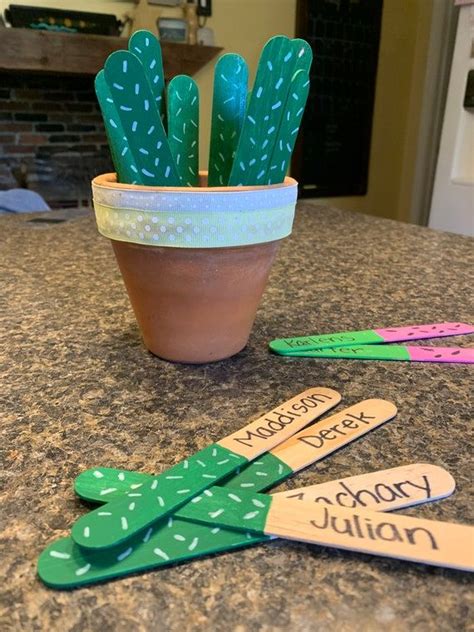 a potted cactus sitting on top of a counter next to some wooden name tags