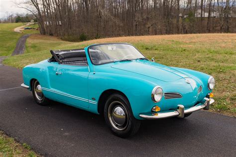 an old blue sports car is parked on the road