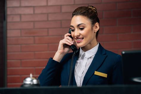 Young Beautiful Hotel Receptionist Receiving Call At Workplace Stock Photo - Download Image Now ...