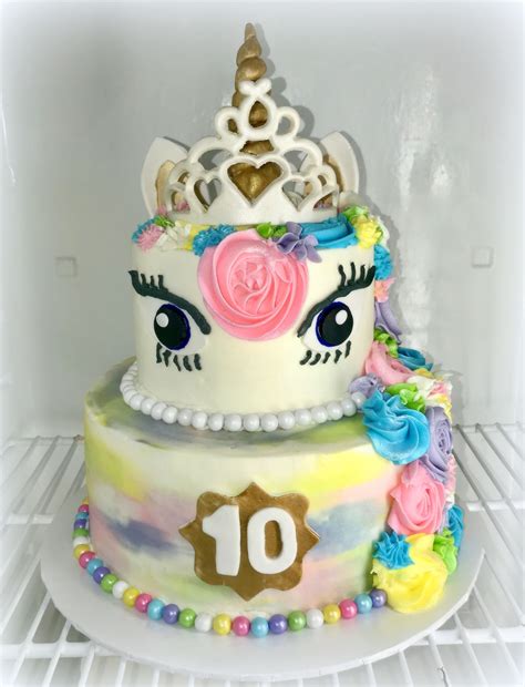 there is a cake decorated with flowers and a unicorn face on the bottom tier in an open refrigerator