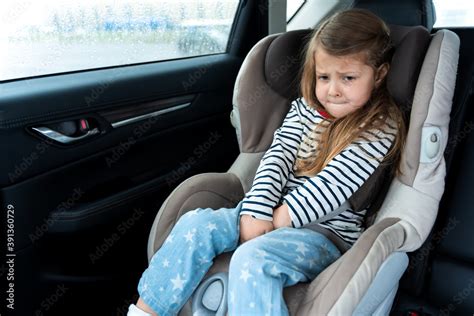 Little girl is driving in car. Kid child wants to go to toilet, pee and endures. Traveling ...