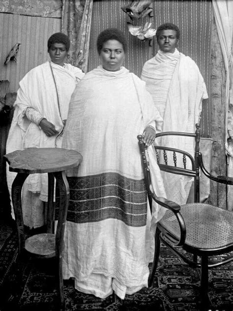 an old black and white photo of three women standing in front of a table with chairs