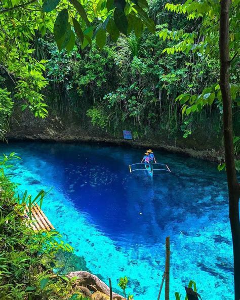 a man on a raft in the middle of a blue pool surrounded by trees and water