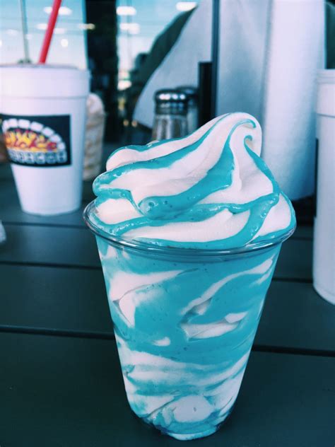 an ice cream sundae with blue and white swirls in a glass cup on a table