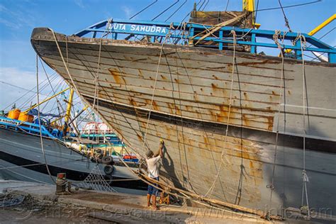 Men Repainting Pinisi Wooden Boat Hull