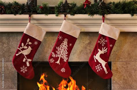 Cozy Christmas fireplace with three red stockings Stock Photo | Adobe Stock