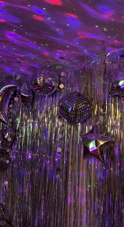 many shiny objects hanging from the ceiling in a room with purple and green lights on it