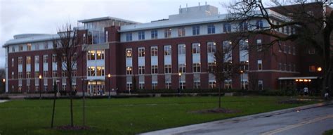 a large building with many windows and lights on it's sides in the evening