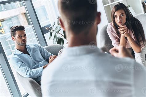 What should we do Young married couple looking at psychologist while sitting on the therapy ...