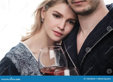 A Couple, a Man and a Woman in Bathrobes Drink Red Wine from Large Glass Goblets in the ...