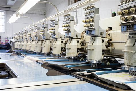 Rows of programmed embroidery machines speed stitching in clothing factory - Stock Photo - Dissolve