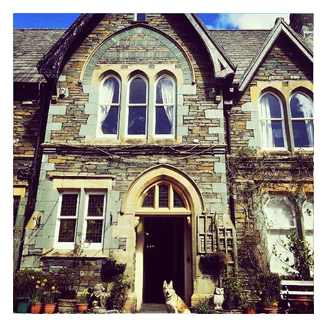 a dog sitting in front of a stone building with large arched windows and an entrance