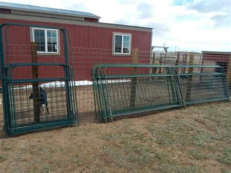 the fence is made of green wire and has two doors on each side that are open