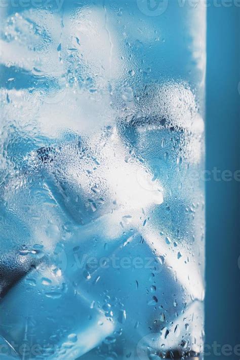 Ice cubes in a glass with refreshing ice water on a blue background ...