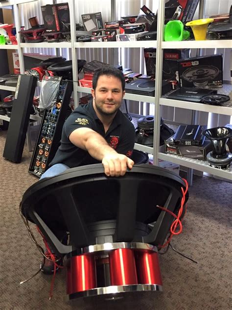 a man sitting on top of a large speaker in a room filled with other electronics