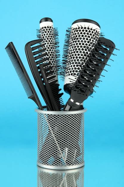 Premium Photo | Iron basket with combs and round hair brushes on color ...