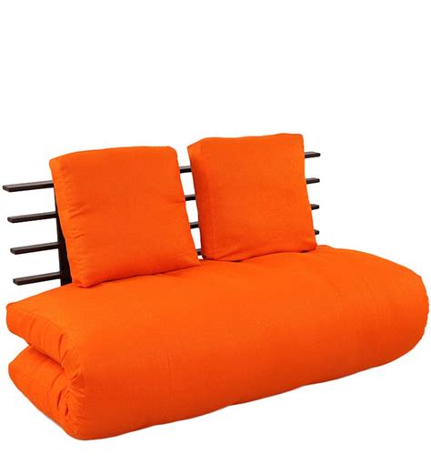 an orange futon bed with two pillows on it and black rails in the back