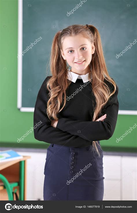 Teenage girl in school uniform standing in classroom Stock Photo by ©belchonock 146077819