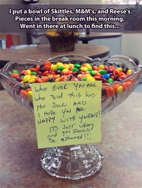 a bowl filled with lots of candy sitting on top of a counter next to a sign