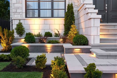 an outdoor area with steps and plants lit up by lights in front of a house