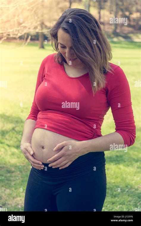 Pregnant woman wearing red shirt gently caressing her belly Stock Photo ...