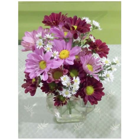a glass vase filled with lots of purple and white flowers on top of a table