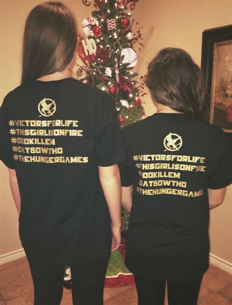 two people standing in front of a christmas tree wearing matching black t - shirts with white ...