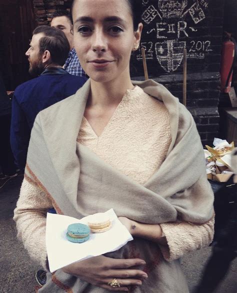 a woman is standing outside holding a box of donuts