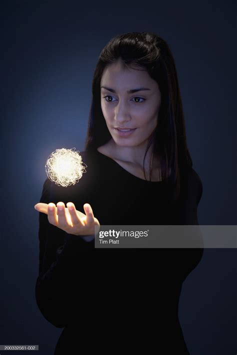 Stock Photo : Young woman holding hand beneath glowing ball of fibre ...