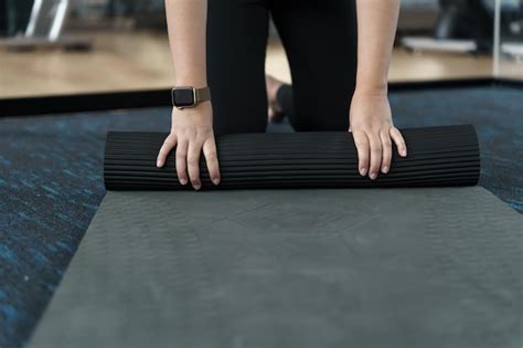 Premium Photo | Fitness woman folding exercise mat before working out in yoga studio rolling ...