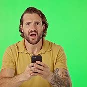Face, green screen and man with smartphone, frustrated and angry ...