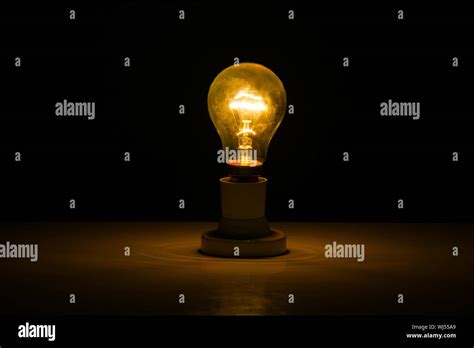 Illuminated light bulb in dark room Stock Photo - Alamy