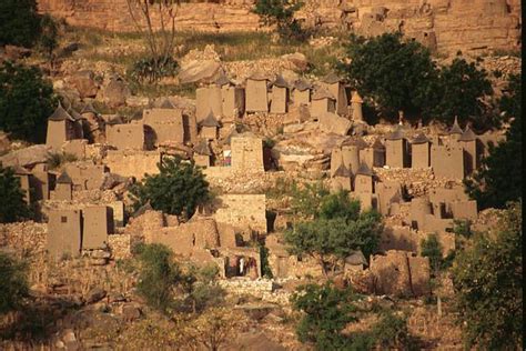 an old village built into the side of a mountain with trees growing out ...