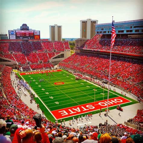 a football stadium filled with lots of red and green fans watching the game on tv