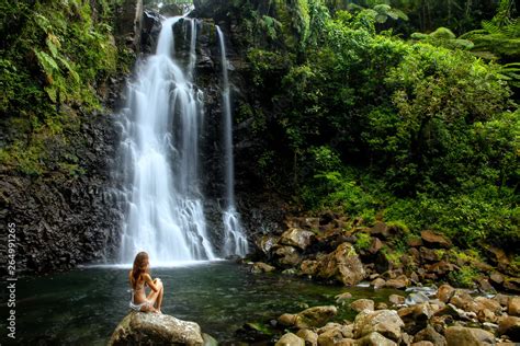 Young woman in bikini sitting by Middle Tavoro Waterfalls in Bouma ...