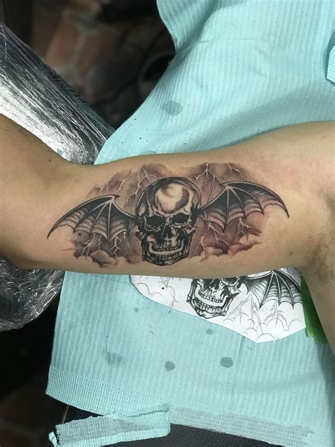 a man with a skull and bat tattoo on his arm