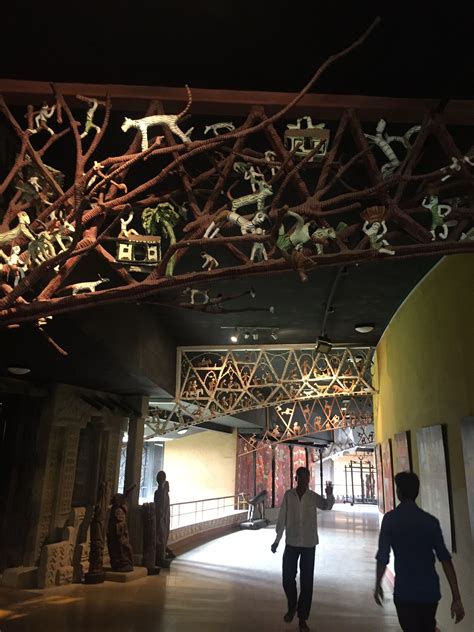 two people walking down a hall with sculptures on the ceiling