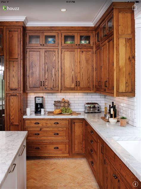 Rich oiled wood shaker cabinets with white tile backsplash and marble ...