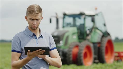 Premium stock video - A young tractor driver uses a tablet