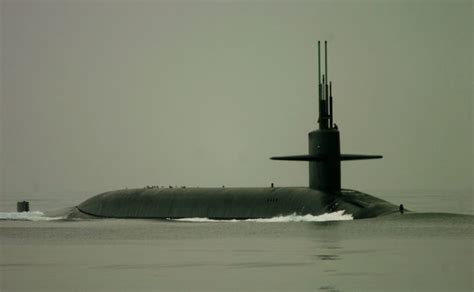 Ohio-class guided-missile submarine USS Georgia, accompanied by two other warships, passes ...